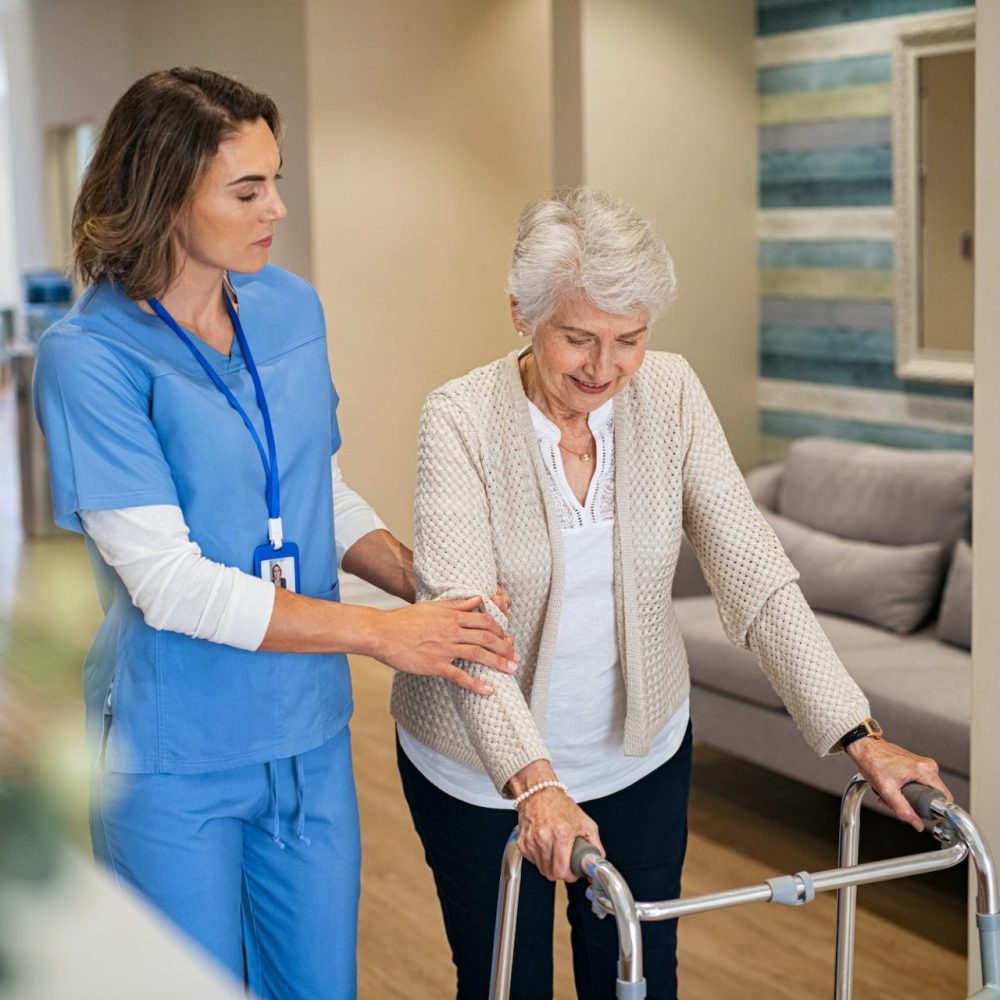 nurse-helping-senior-woman-to-walk-at-private-clinic-e1691999948466