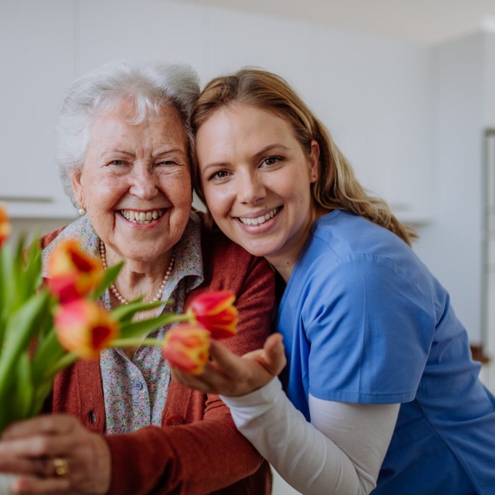 senior-woman-and-nurse-with-tulip-bouquet--e1692611923140